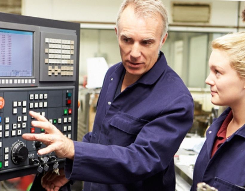 Man showing a woman how to operate a machine.